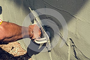 Construction worker holding plastering trowel smoothing wall defects