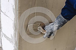 Construction worker holding plastering trowel smoothing wall defects