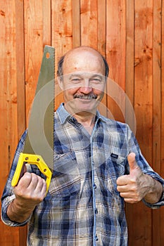 Construction worker holding a saw and showing thumbs up approval