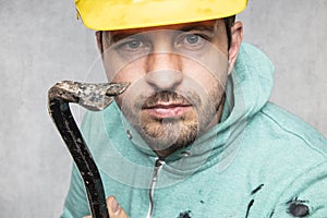 The construction worker holds a work tool in his hands, a crowbar