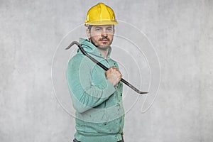 The construction worker holds a work tool in his hands, a crowbar