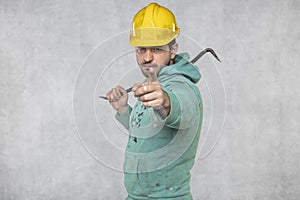 The construction worker holds a work tool in his hands, a crowbar