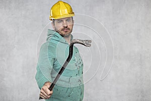 The construction worker holds a work tool in his hands, a crowbar