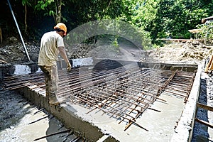 Construction worker inspecting rebar grid on concrete foundation