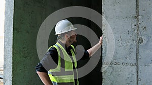 A construction worker inspects the wall of a building on a construction site.