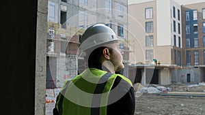 A construction worker inspects the wall of a building on a construction site.
