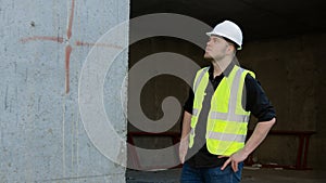 A construction worker inspects the wall of a building on a construction site.
