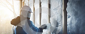 Construction worker installing house wall insulation in new home