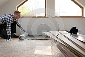 Construction worker installing laminate floor in a new renovated attic. Home improvement concept