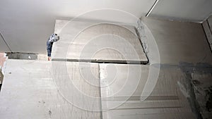 Construction worker installing large ceramic tiles on the wall.