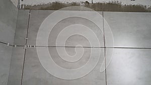 Construction worker installing large gray tiles on wall.