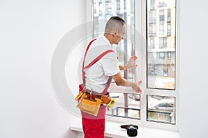 Construction worker installing plastic window in house