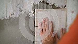 Construction worker installing small ceramic tiles on the wall.