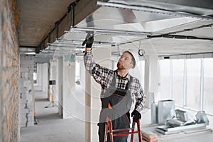 Construction worker installing ventilation system in building under construction
