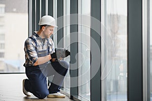 Construction worker installing window using cordless drill in modern building