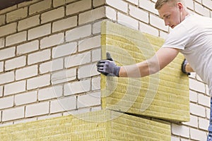 Construction worker insulating house facade with mineral wo photo