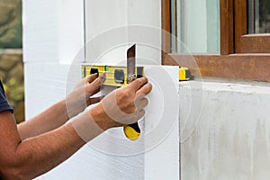 Construction worker insulating house wall with styrofoam insulatuion sheet