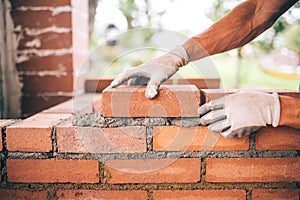 construction worker laying bricks and building barbecue in industrial site. Detail of hand adjusting bricks
