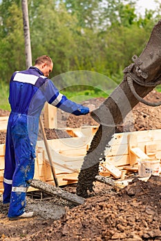 Construction worker laying cement or concrete into the foundation formwork