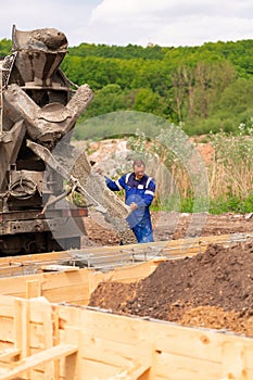 Construction worker laying cement or concrete into the foundation formwork