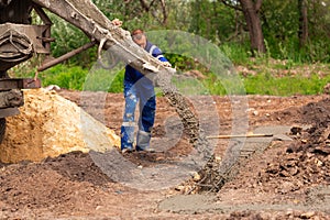 Construction worker laying cement or concrete into the foundation formwork