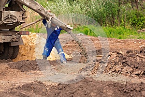 Construction worker laying cement or concrete into the foundation formwork