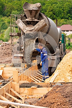 Construction worker laying cement or concrete into the foundation formwork