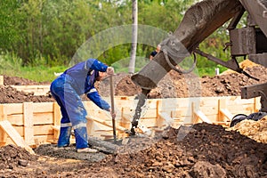 Construction worker laying cement or concrete into the foundation formwork