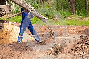 Construction worker laying cement or concrete into the foundation formwork