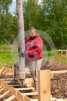 Construction worker laying cement or concrete into the foundation formwork with automatic pump