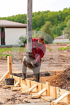 Construction worker laying cement or concrete into the foundation formwork with automatic pump