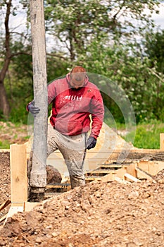 Construction worker laying cement or concrete into the foundation formwork with automatic pump