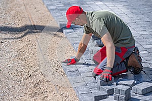 Construction worker laying paving stones on a pathway at a construction site
