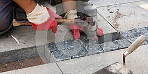 Construction worker laying stone cobbles in sand