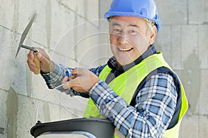 construction worker with long trowel plastering wall