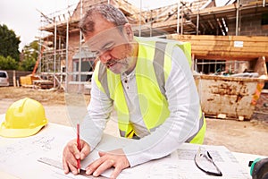 Construction Worker Looking At Plans On Building Site