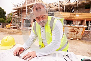 Construction Worker Looking At Plans On Building Site