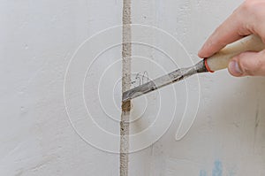 Construction worker makes a hole in the wall for electrical wiring with a chisel