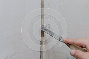 Construction worker makes a hole in the wall for electrical wiring with a chisel