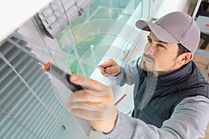 Construction worker man install blinds on plastic white upvc windows