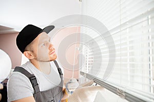 Construction worker man install blinds on plastic white upvc windows in house