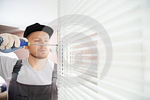 Construction worker man install blinds on plastic white upvc windows in house