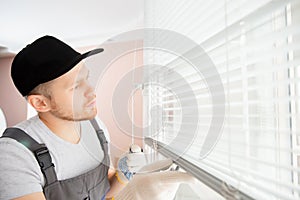 Construction worker man install blinds on plastic white upvc windows in house