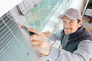 Construction worker man install blinds on windows