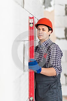 Construction worker man observing and surveying wall alignment using water level
