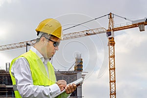 Construction worker man with safety helmet and vest works at construction site. Concept of people working in industrial field