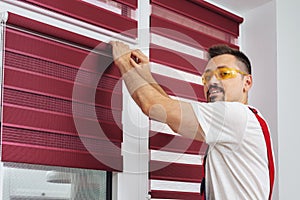 Construction worker man in a uniform install blinds look at camera and smiling