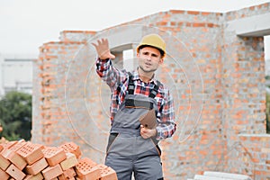 Construction worker man in work clothes and a construction helmet. Portrait of positive male builder in hardhat working