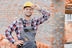 Construction worker man in work clothes and a construction helmet. Portrait of positive male builder in hardhat working