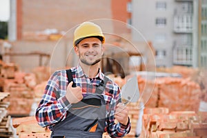 Construction worker man in work clothes and a construction helmet. Portrait of positive male builder in hardhat working